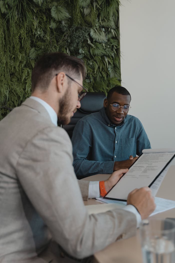 Two men in a modern office setting discussing a document during a business meeting.